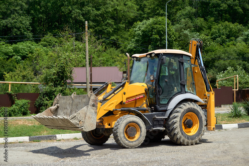 Quadro su tela Compact Backhoe Loader in a Green Urban Periphery