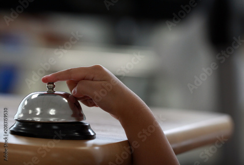 Foto Close-up of a kid ringing a chrome reception bell call button for attention or service with blurred background