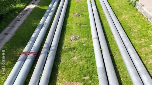 Aerial view of industrial pipes for gas, water, and oil running parallel across a green landscape, showcasing their weathered surfaces and surrounding vegetation in a natural setting