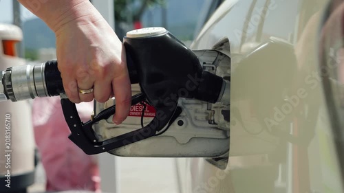 Close-up of a fuel nozzle inserted into a car fuel tank at a gas station. Concept of rising fuel prices, energy crisis, oil market volatility, inflation, transportation costs, and the economic impact