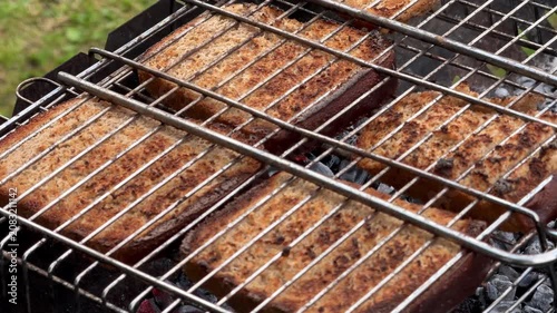 Slices of bread toasting on a metal grill over hot charcoal outdoors. Barbecue cooking, campfire food, rustic picnic, outdoor meal, summer