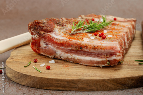 Raw marinated pork ribs with rosemary, spices and garlic on a wooden cutting board with a meat fork