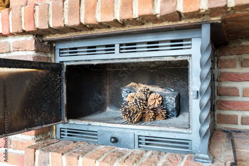 Kaminofen mit Feuerholz und Tannenzapfen