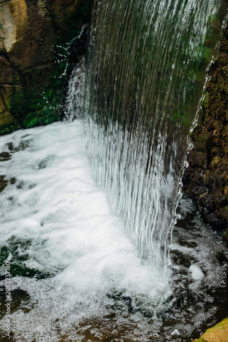 A small decorative waterfall in the city park. Clean, refreshing water.