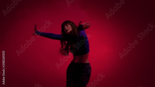 Contemporary dance solo with expressive arm pose in red studio light