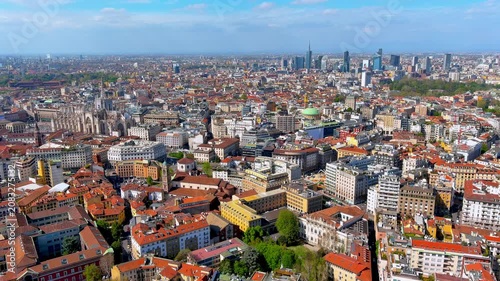 Aerial drone view of Milan cityscape with the Duomo, historic centre rooftops, and the Porta Nuova skyscraper skyline behind, Lombardy, Italy, spring daytime.