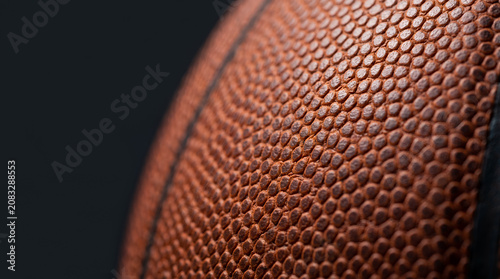 Extreme macro close-up of a basketball pebble texture and black seam against a dark background