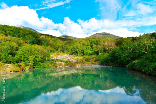 Jigokunuma pond with volcanic gas steam and sky reflection in Hakkoda