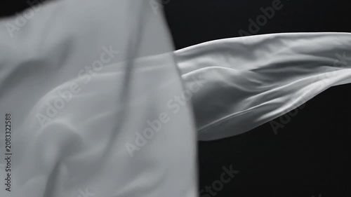 Elegant white silk fabric flowing against a black background