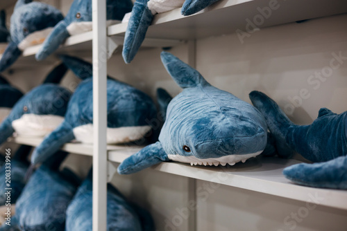Obraz na plátně Soft plush shark toys displayed on shelves in a toy store.