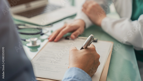Photography Doctor assisting patient with medical form