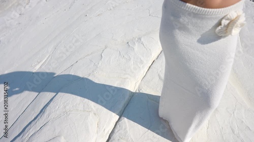 Woman wearing a white skirt standing barefoot on a white marl rock