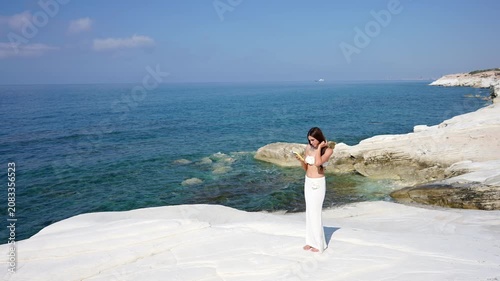Elegant woman texting on her phone on a white rocky coast