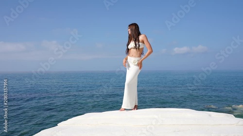 Beautiful woman in white enjoying the summer sun on a white cliff