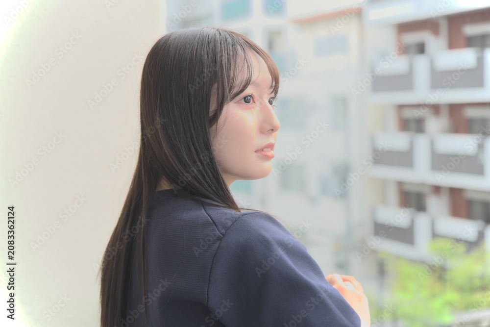 Fototapeta premium ベランダから見える景色を眺めて休憩する女性