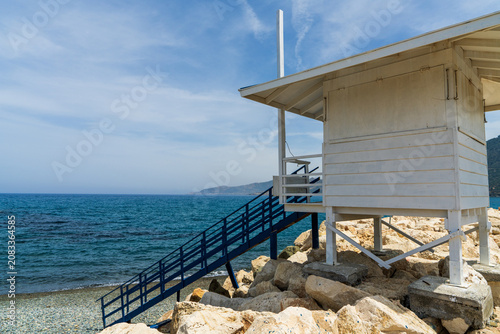 White wooden lifeguard tower on beach in Pomos, Cyprus. Peaceful Mediterranean coastline, beach safety, summer travel, seaside relaxation and coastal tourism concept.