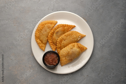 Cuadro en lienzo White plate of golden fried turnovers with red dipping sauce