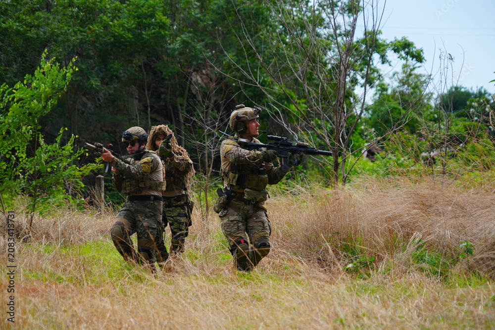 Fototapeta premium group of soldiers in military uniforms carrying BB guns were randomly attacked and taken down during a military exercise while playing a game.