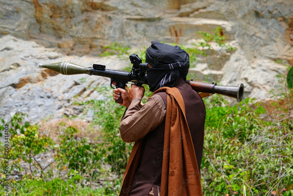 Fototapeta premium A Muslim man wearing a face covering and holding a gun is randomly shooting at another person during a training exercise while playing a BB gun game.