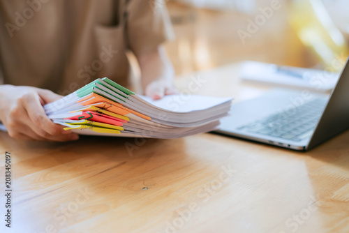 Foto Businesswoman Organizing Paperwork with Color-Coded Document Files and Laptop on