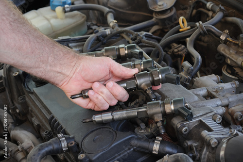 Detail of modern diesel engine repair, closeup of injector in mechanic hand, common rail system