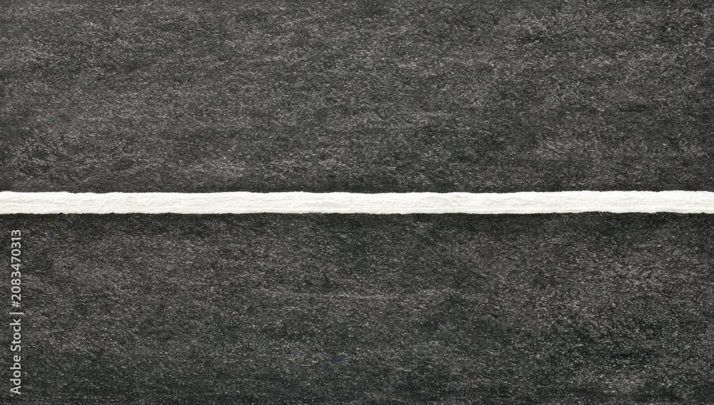 Fototapeta premium A stark white line bisects a dark, textured surface, creating a clean division
