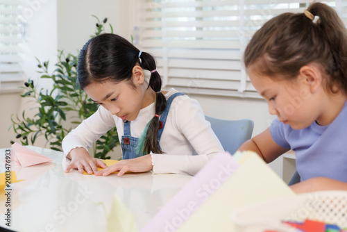 Canvas Print Asian preteen girl folding yellow paper with care during classroom origami proje