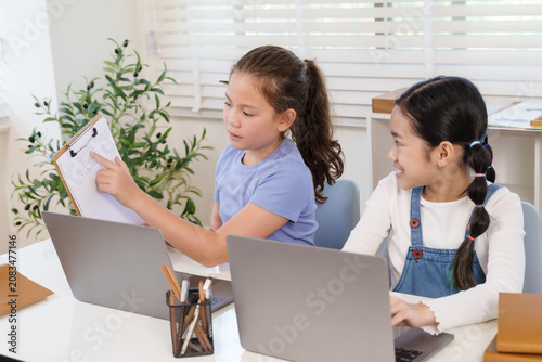 Foto Caucasian student presenting assignment clipboard to asian classmate laptop desk