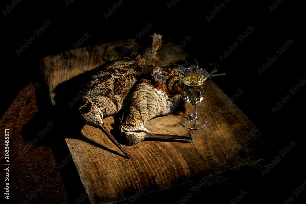 Fototapeta premium Woodcock game birds on rustic wooden table with glass of white wine