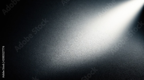 A bright spotlight shines down on a textured, dark background
