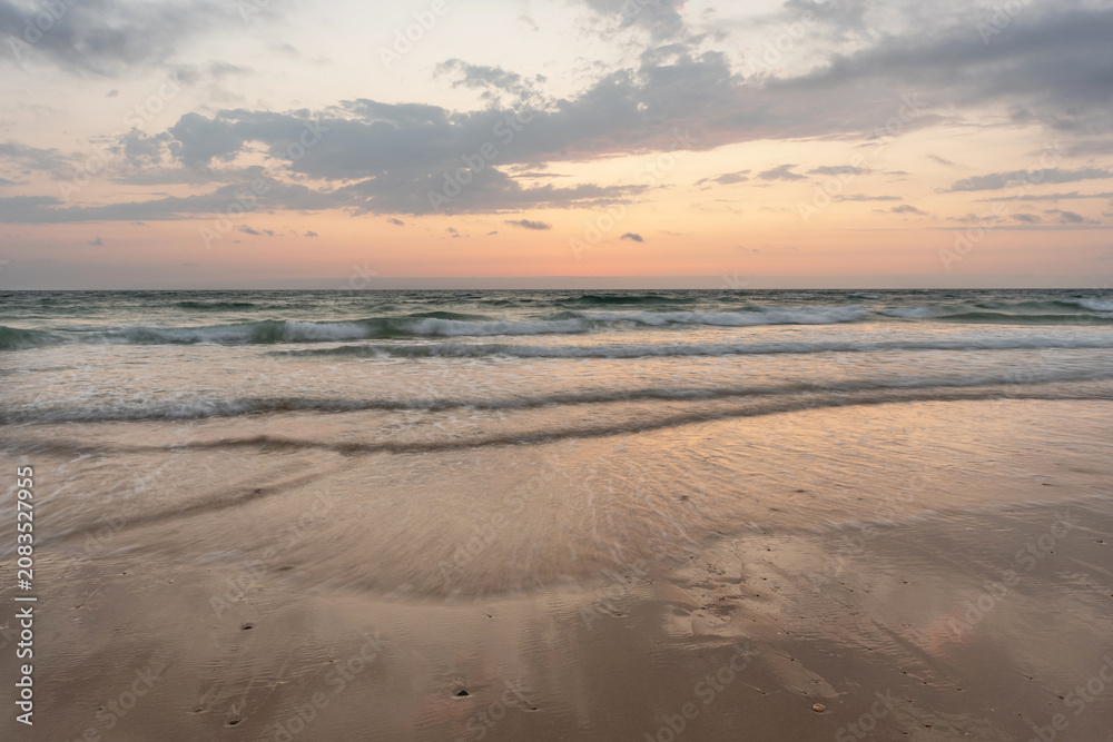 Obraz premium Sunset on the beach with moving waves 