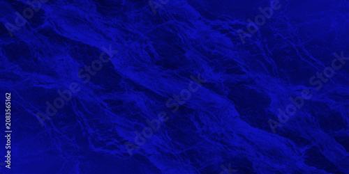 Abstract textured deep royal blue marble liquid fluid background surface with flowing veins for intense majestic backdrop design