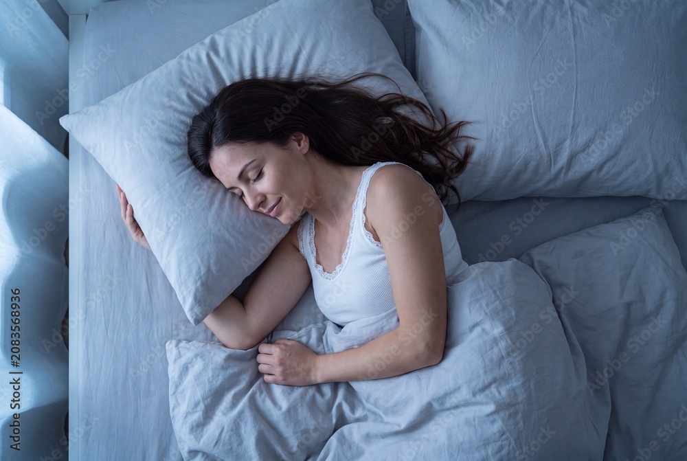 Fototapeta premium Young woman sleeping peacefully in bed at night