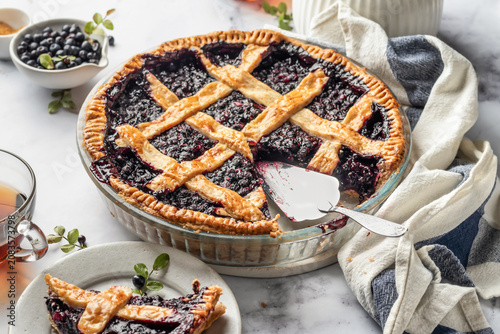 Photos Blueberry pie with lattice crust sliced on white marble table, traditional homem