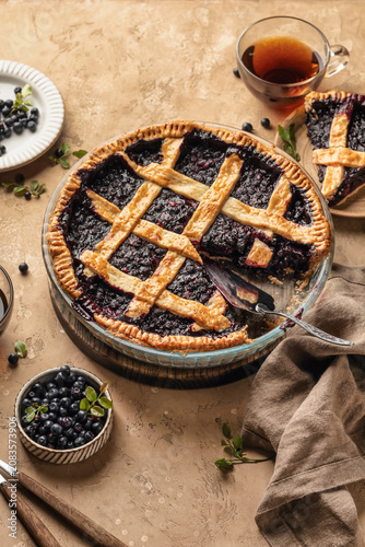 Blueberry pie with lattice crust sliced on brown textured table background, traditional homemade dessert