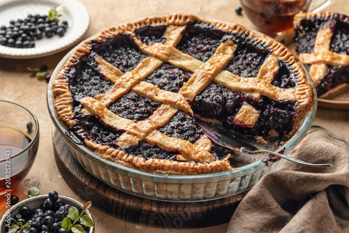 Blueberry pie with lattice crust sliced on brown textured table background, traditional homemade dessert