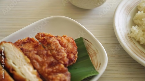 Fried chicken with rice and green leaf on a white plate
