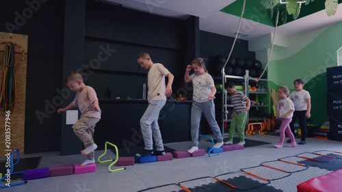 Children perform a balance and coordination exercise in a fitness class. Young students are actively engaged in a physical activity course.