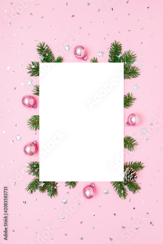 Christmas, New Year vertical frame of fir tree branches, Christmas baubles, decorations on pink and white flat lay background. Perfect for holiday greetings, banners, social media. Copy space