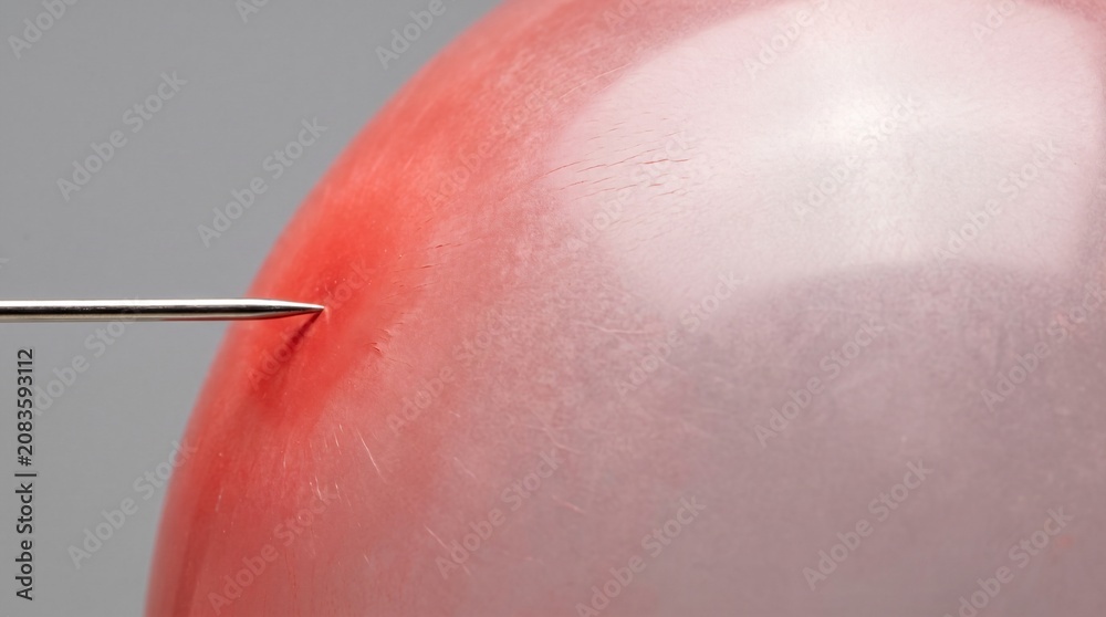 Fototapeta premium Over-Inflated Red Balloon Meeting a Sharp Needle as a Pressure and Risk Metaphor