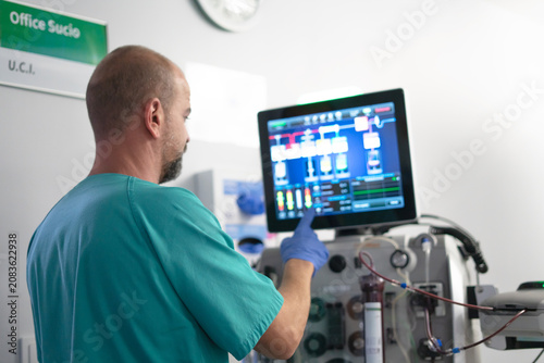 Medical professional operating advanced medical equipment screen in an icu