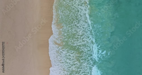 aerial top view The waves slowly swept towards the shore.
White foam waves in the bright green sea lapping on the white sandy beach.
white bubble waves, and clear sand landscape. freedom beach.