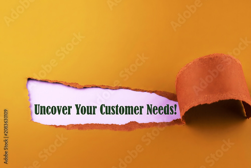 Uncover Your Customer Needs Message Revealed Through Torn Paper On mustard orange Background For Marketing Research And Business Strategy Concept