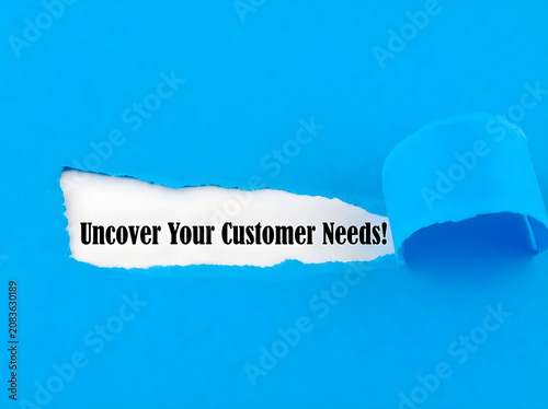 Uncover Your Customer Needs Message Revealed Through Torn Paper On solid blue Background For Marketing Research And Business Strategy Concept