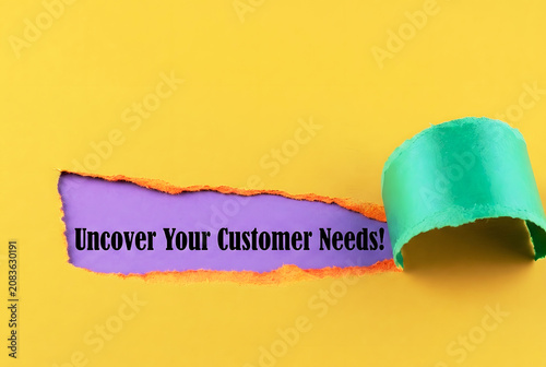 Uncover Your Customer Needs Message Revealed Through Torn Paper On Vibrant Yellow Background For Marketing Research And Business Strategy Concept