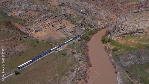 Distant passenger train moves along a riverbank (Dogu Ekspresi)