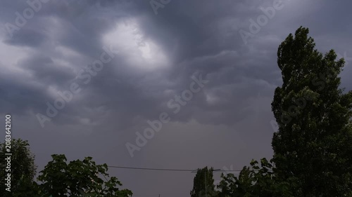 Ominous dark thunderstorm clouds flashing with hidden lightning in dramatic sky