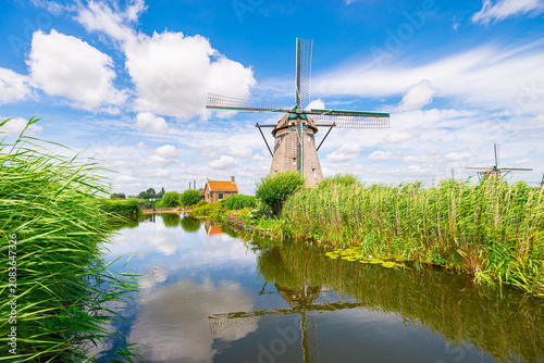Cuadro en lienzo Traditional Dutch windmill over calm water with reflection in lush countryside l