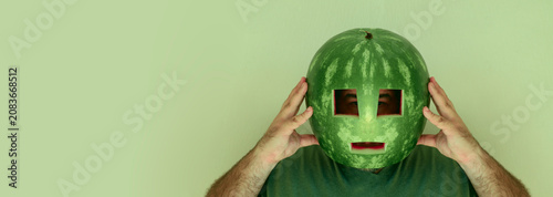 Crazy man wearing watermelon as helmet, hard hat on head  male isolated on white wall background. idea of protection insurance man in a watermelon helmet on his head. baseball hardball concept idea