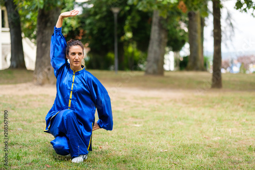 Фотография Woman practicing tai chi in blue uniform outdoors